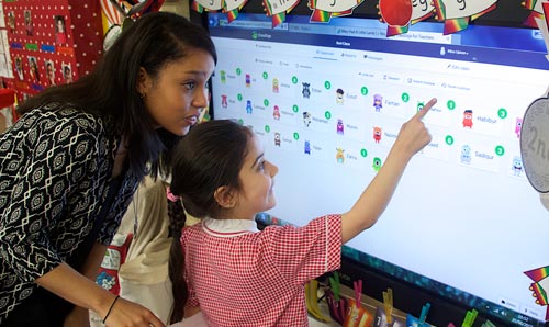 Pupil and teacher using touch screen display in classroom