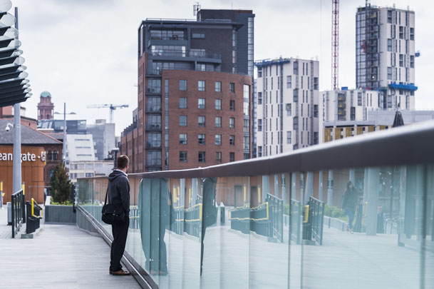 Man stood on a bridge looking at a city