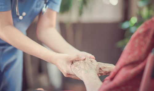 Hand of an elderly woman with her carer at home