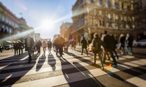 A crowd of anonymous people walking on a busy street.