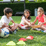 An image of children seated in a green space.