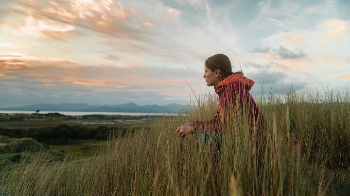 Student sat in long grass at the beach