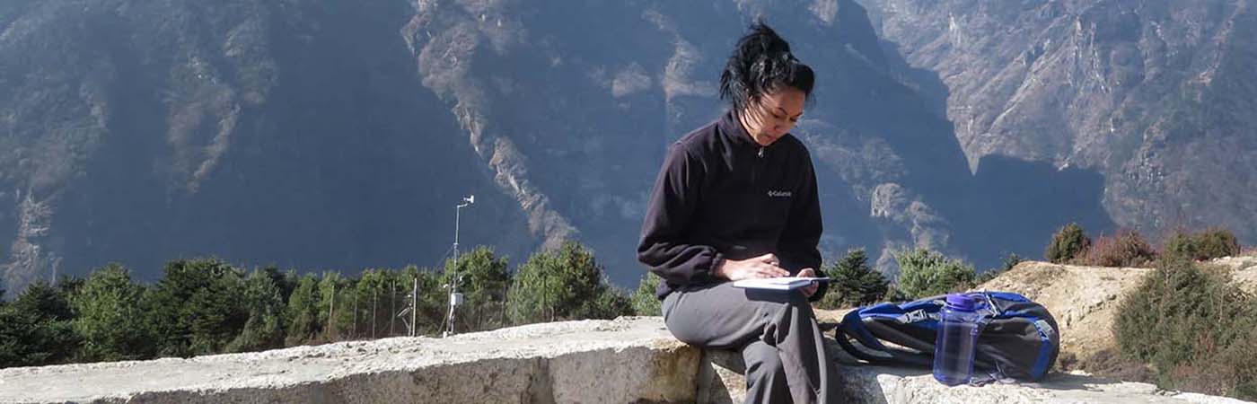 Academic making notes with mountains in the background